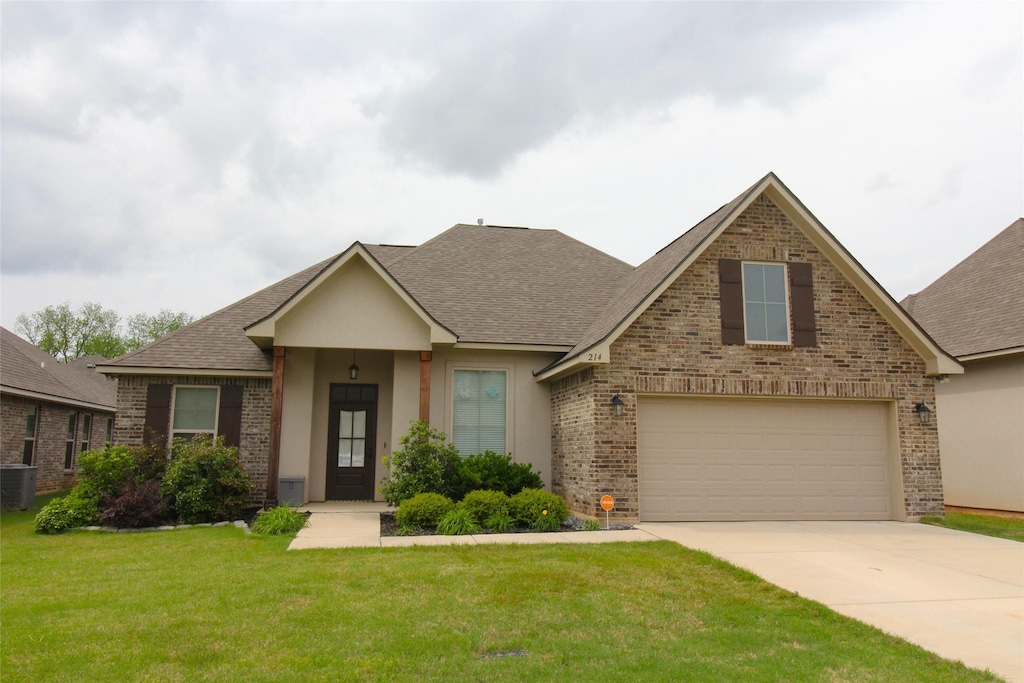 214 Hyperion St, Bossier City, LA 71111 - view of front of property featuring a front lawn, driveway, stucco siding, brick siding, and roof with shingles