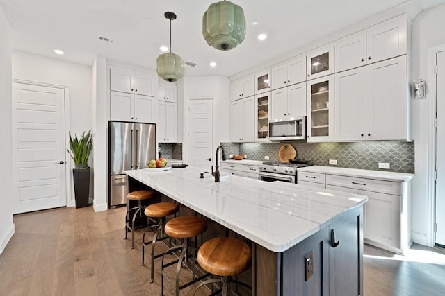 kitchen featuring stainless steel appliances, a kitchen breakfast bar, a sink, and white cabinetry