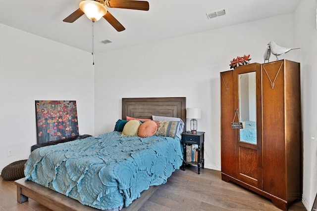 bedroom featuring wood finished floors, visible vents, and a ceiling fan