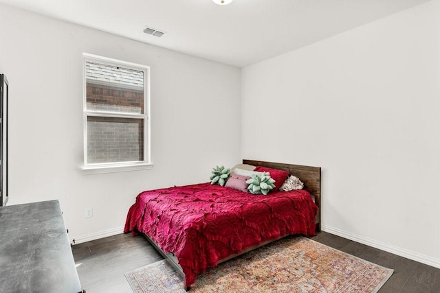 bedroom featuring baseboards, wood finished floors, and visible vents