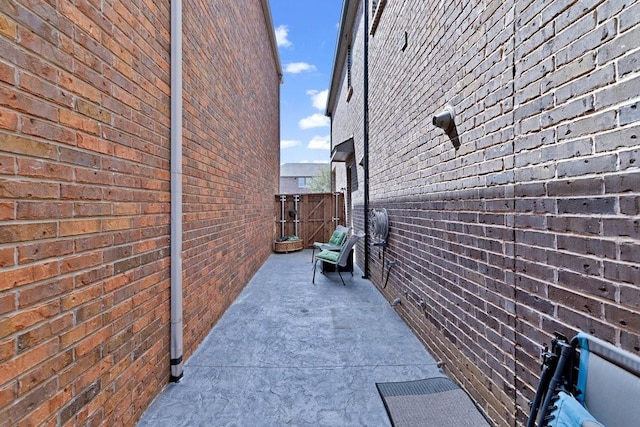 view of side of property with fence, brick siding, and a patio
