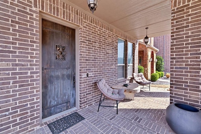 view of exterior entry featuring covered porch and brick siding