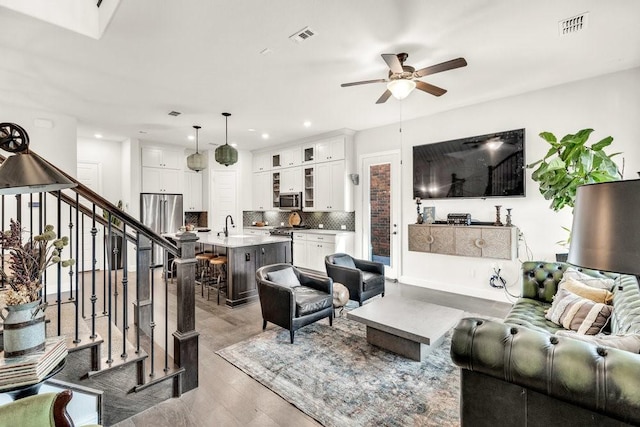 living area with stairs, ceiling fan, light wood-style flooring, visible vents, and recessed lighting