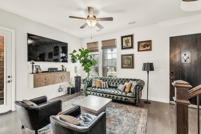 living area with baseboards, a ceiling fan, wood finished floors, and visible vents