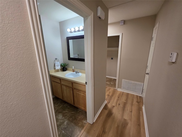 bathroom featuring wood finished floors, visible vents, vanity, and baseboards