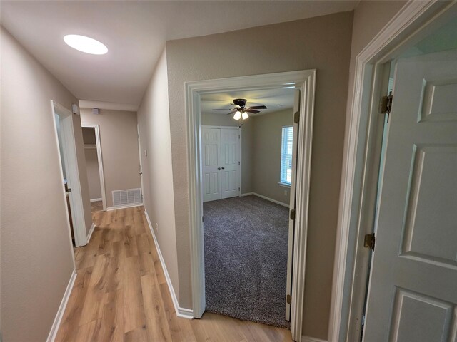 corridor featuring baseboards, visible vents, and light wood-type flooring