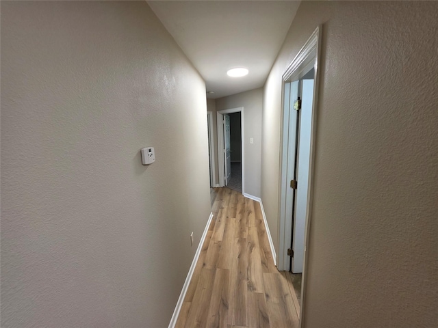 hallway featuring light wood-type flooring and baseboards