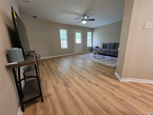 living room with visible vents, ceiling fan, light wood finished floors, and baseboards