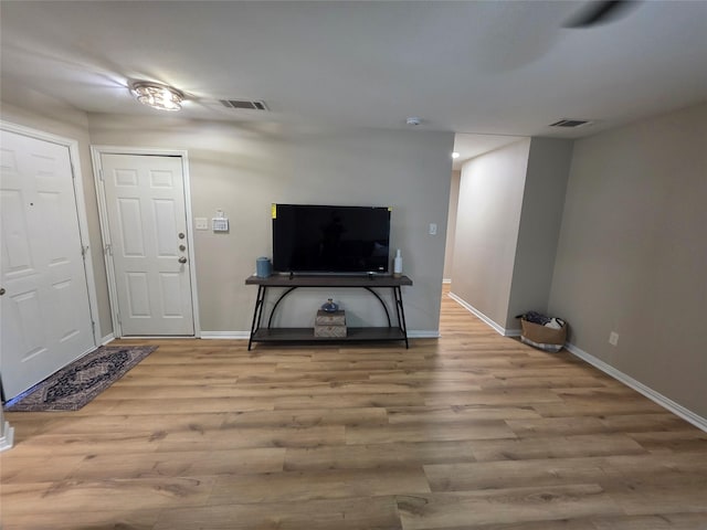 living area featuring baseboards, visible vents, and wood finished floors