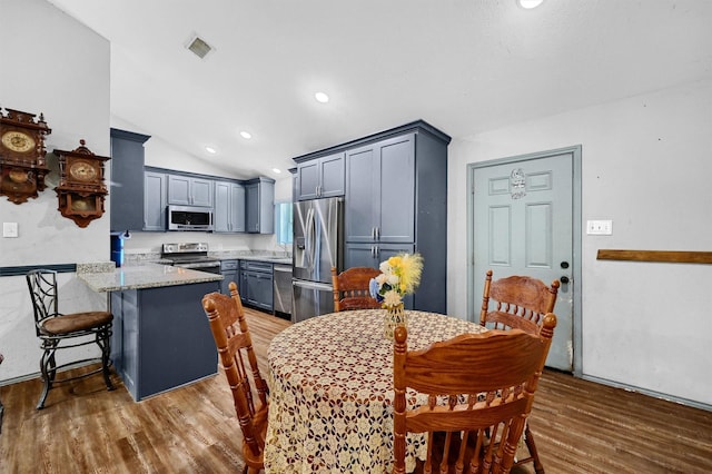 dining area with lofted ceiling, recessed lighting, wood finished floors, and visible vents
