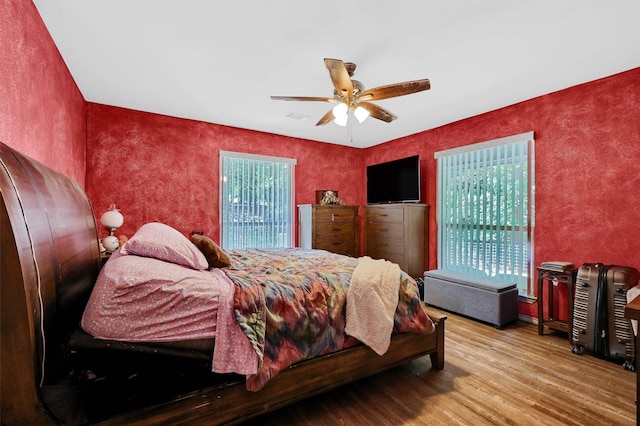 bedroom featuring a ceiling fan, visible vents, and wood finished floors