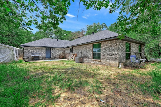 back of house featuring brick siding, central AC, and a shingled roof