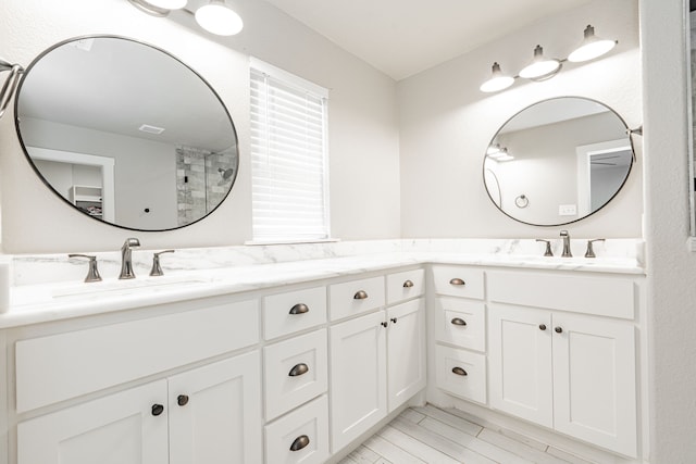 bathroom featuring a shower, visible vents, a sink, and double vanity
