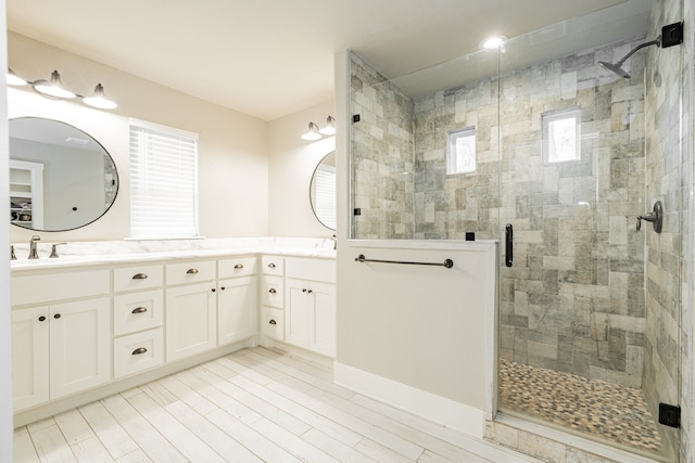 bathroom featuring double vanity, a stall shower, and a sink