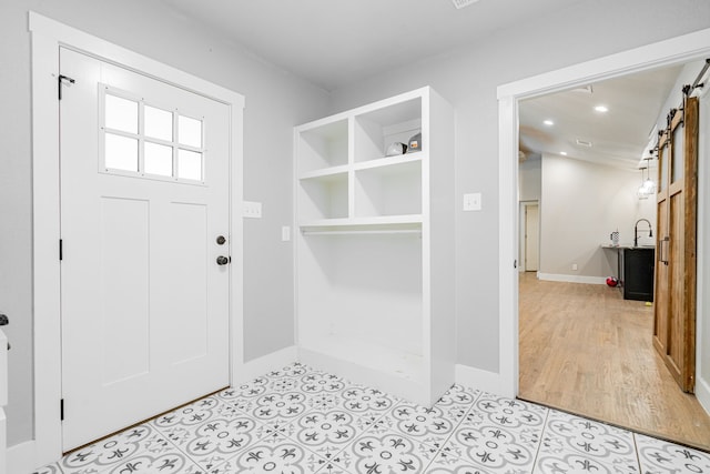 mudroom featuring a barn door, baseboards, and recessed lighting