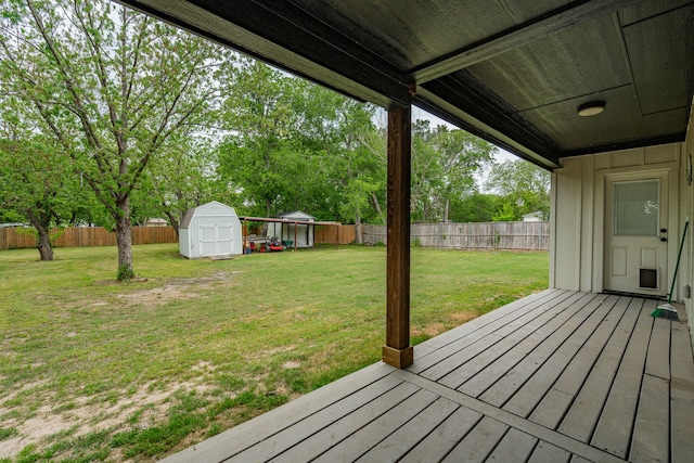 wooden terrace with a fenced backyard, an outbuilding, a yard, and a shed
