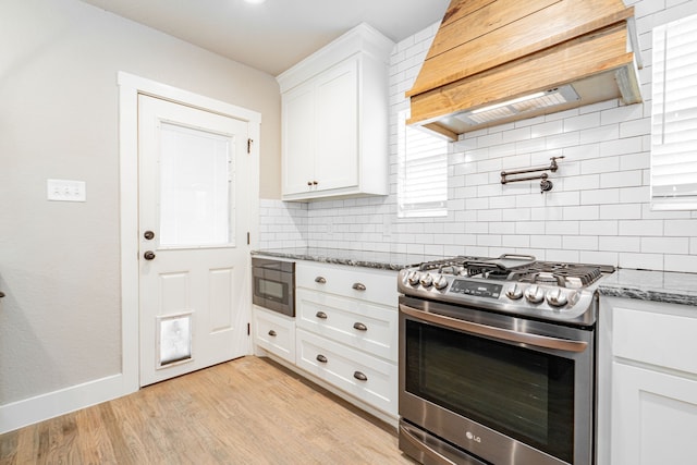 kitchen featuring custom exhaust hood, tasteful backsplash, light stone countertops, and stainless steel gas stove