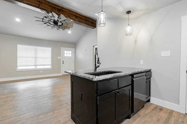 kitchen with stainless steel dishwasher, a sink, lofted ceiling with beams, light wood-style floors, and dark cabinetry