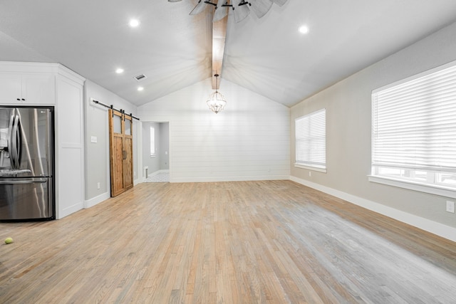 unfurnished living room with a barn door, lofted ceiling with beams, light wood-style floors, baseboards, and visible vents