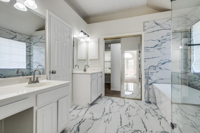 full bathroom with two vanities, a soaking tub, marble finish floor, and a sink