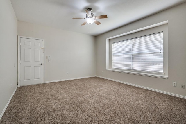 carpeted spare room with a ceiling fan and baseboards