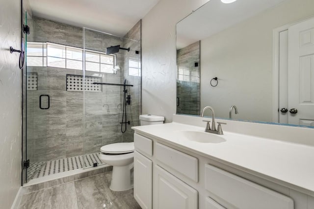 bathroom featuring toilet, vanity, and a stall shower
