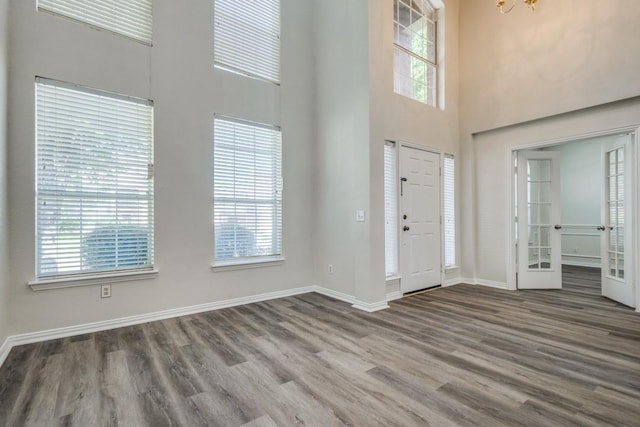 foyer with a high ceiling, french doors, wood finished floors, and baseboards