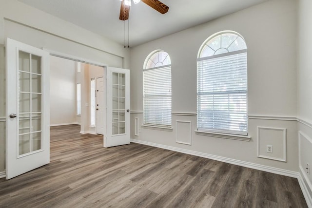 interior space with baseboards, a ceiling fan, french doors, and wood finished floors