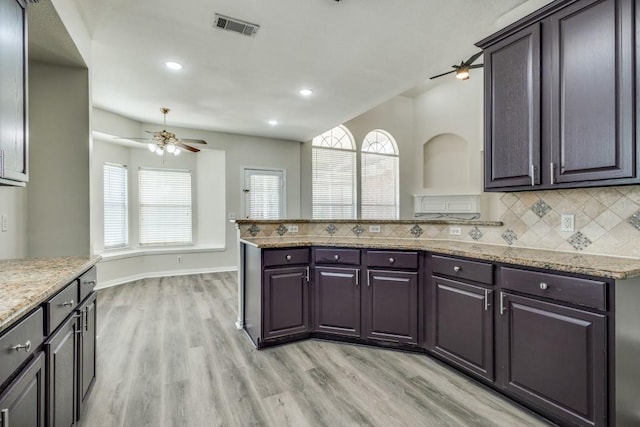kitchen featuring light wood finished floors, visible vents, a peninsula, tasteful backsplash, and ceiling fan