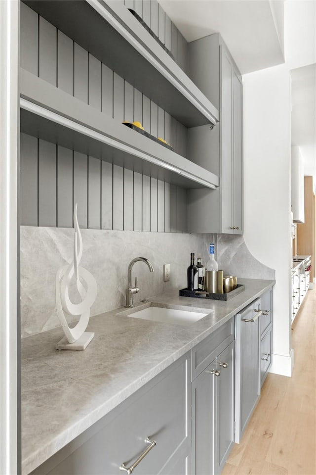 11736 Jamestown Rd, Dallas, TX 75230 - kitchen featuring a sink, a large island with sink, appliances with stainless steel finishes, light wood-style flooring, and beamed ceiling