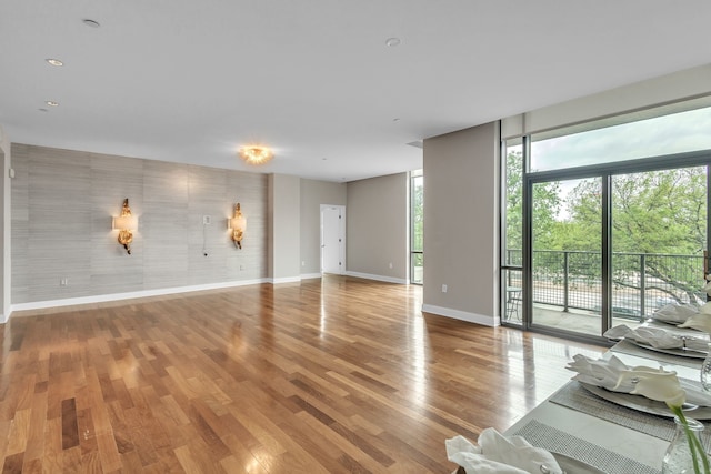 unfurnished living room featuring a wall of windows, wood finished floors, and baseboards