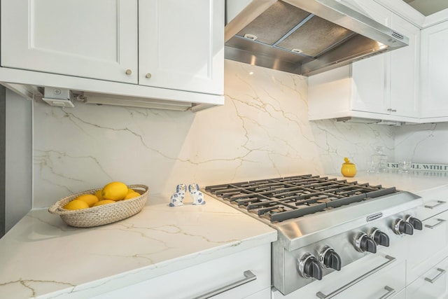 kitchen featuring stainless steel gas cooktop, tasteful backsplash, white cabinetry, and wall chimney range hood