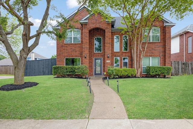 view of front of property featuring fence, a front lawn, brick siding, and roof with shingles