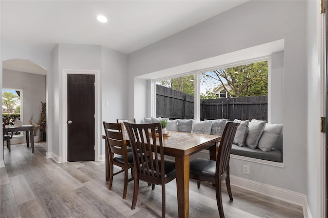 dining space with plenty of natural light, baseboards, arched walkways, and light wood-style floors