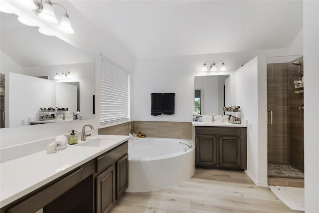 bathroom with wood finished floors, a sink, a shower stall, and a tub with jets