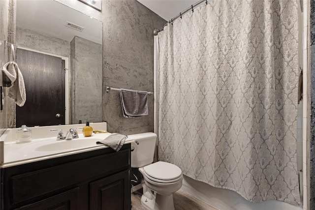 bathroom featuring wood finished floors, vanity, shower / bath combination with curtain, toilet, and visible vents