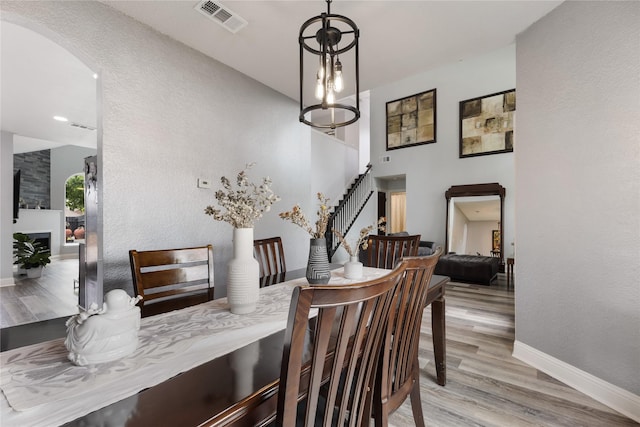 dining area with stairway, light wood finished floors, visible vents, arched walkways, and baseboards