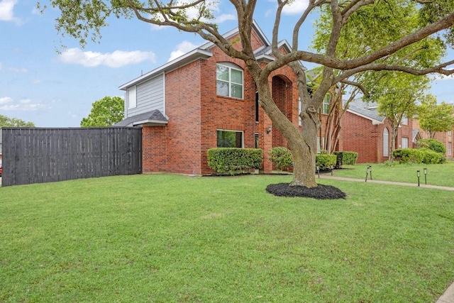 traditional-style home with fence, a front lawn, and brick siding