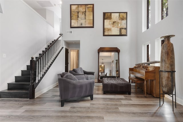interior space with wood finished floors, stairs, baseboards, a high ceiling, and visible vents