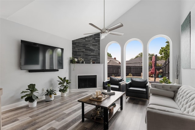 living area featuring a large fireplace, a wealth of natural light, a ceiling fan, and high vaulted ceiling