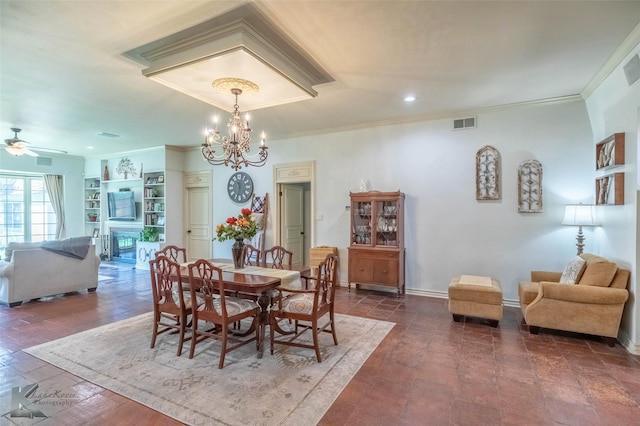 dining room with a fireplace, visible vents, crown molding, and ceiling fan with notable chandelier