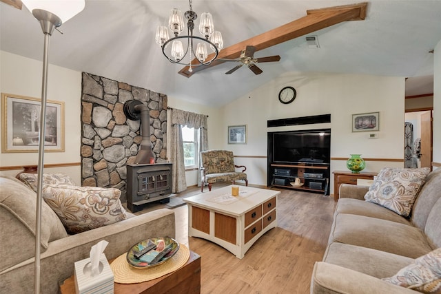 living room featuring light wood finished floors, vaulted ceiling with beams, visible vents, ceiling fan, and a wood stove