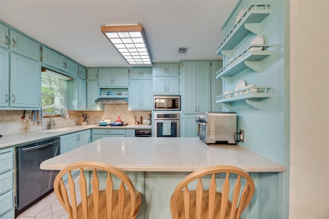 kitchen with open shelves, a sink, decorative backsplash, a peninsula, and appliances with stainless steel finishes