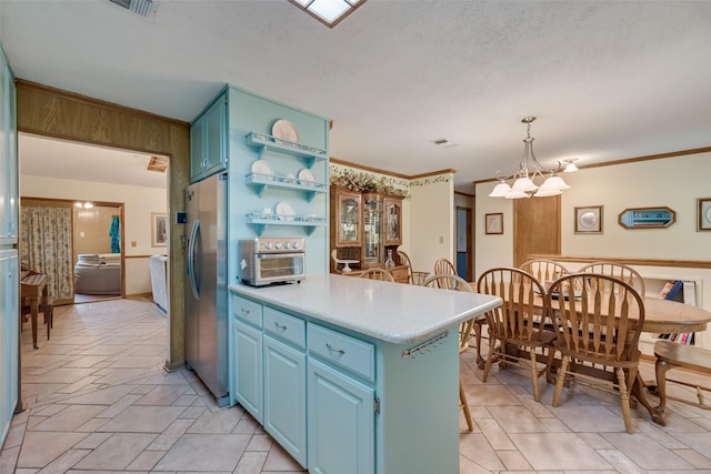 kitchen featuring light countertops, open shelves, visible vents, freestanding refrigerator, and blue cabinetry
