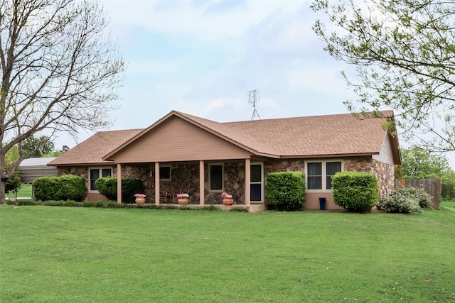 view of front of home featuring stone siding, a shingled roof, and a front yard