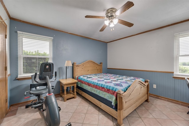 bedroom with light tile patterned floors, baseboards, ornamental molding, and wainscoting