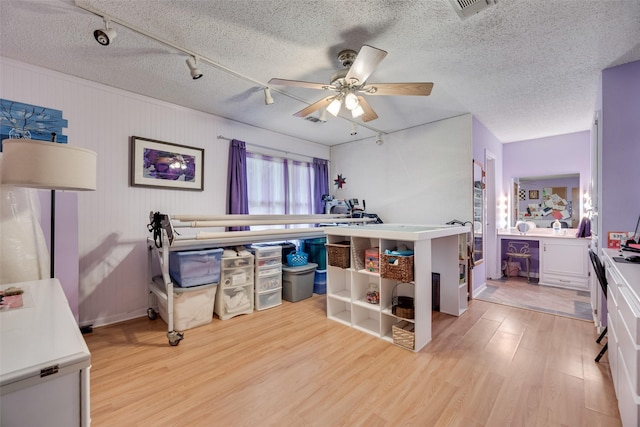 bedroom with track lighting, a textured ceiling, light wood finished floors, and visible vents
