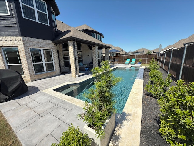 view of swimming pool with a patio, a fenced backyard, and a pool with connected hot tub
