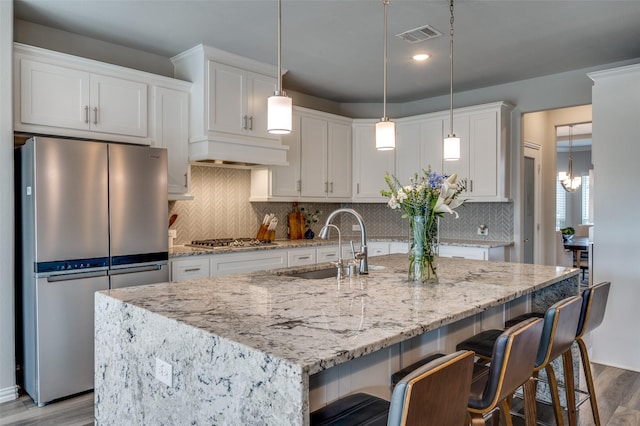 kitchen with wood finished floors, recessed lighting, white cabinets, a sink, and appliances with stainless steel finishes