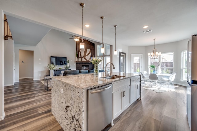 kitchen featuring visible vents, appliances with stainless steel finishes, light stone countertops, a sink, and a glass covered fireplace